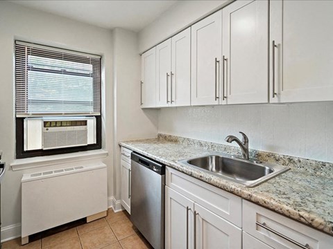 a kitchen with white cabinets and a sink and a window